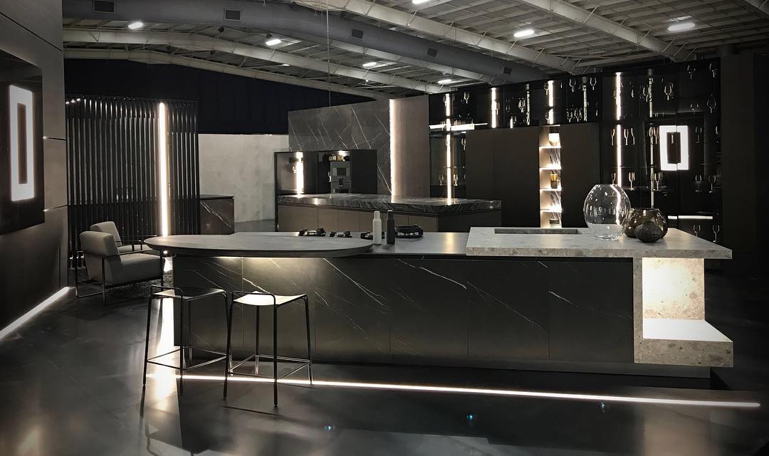 Showroom kitchen with marble-veined stone worktops and a curved breakfast counter